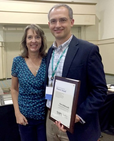 Peter Bobkowskie, right, of the University of Kansas accepts the Pioneer Award from NSPA board member Jeanne Acton at the Nov. 14 adviser awards lunch at the Orlando NSPA/JEA national convention.